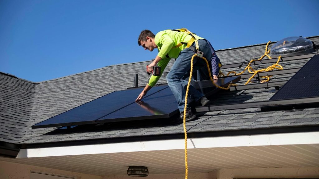 Instalador hace un mantenimiento de instalación de paneles solares sobre tejado de vivienda unifamiliar